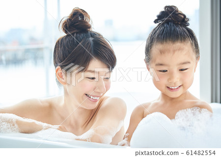 Mother and daughter taking a bubble bath bright bathroom 61482554