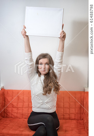 Woman sitting on a sofa and holding outstretched Woman sitting on a sofa and holding outstretched 61488798