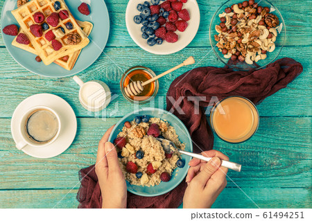 Breakfast table with waffles, oatmeal, cereals, coffee, juice and fresh berries 61494251