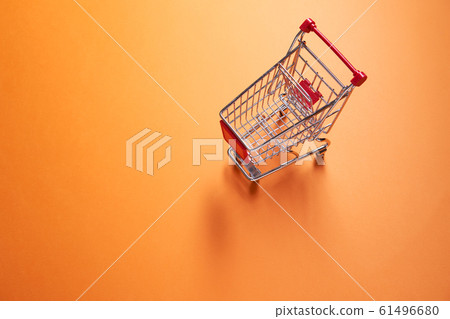 Iron small supermarket trolley on empty orange background 61496680