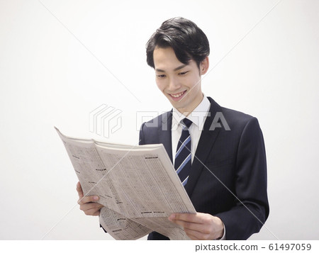 Smiling businessman looking at stock column in newspaper Smiling businessman looking at stock column in newspaper 61497059
