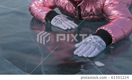 Girl walking on cracked ice of a frozen lake Baikal. Woman traveler explores and looks at an ice floe. It is magical purest place in nature. Girl walking on cracked ice of a frozen lake Baikal. Woman traveler explores and looks at an ice floe. It is magical purest place in nature. 61501224