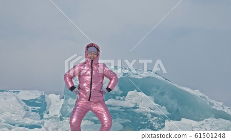 Girl walking on cracked ice of a frozen lake Baikal. Woman traveler explores and looks at an ice floe. It is magical purest place in nature. 61501248