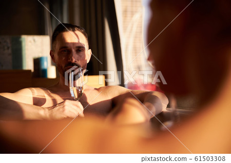 Adult man holding glass of champagne in bathtub Adult man holding glass of champagne in bathtub 61503308