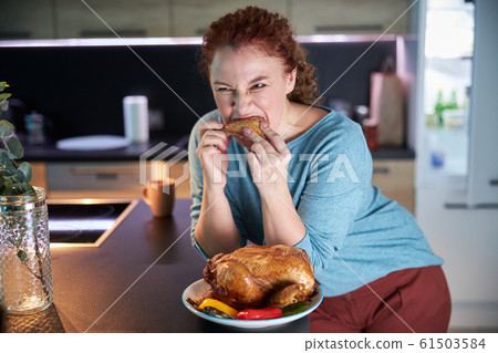 Woman eating roasted chicken at home stock photo Woman eating roasted chicken at home stock photo 61503584