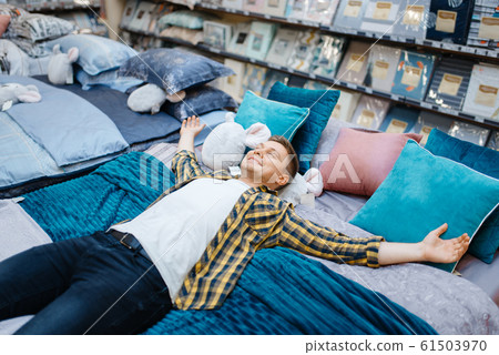 Young man lying on the bed in bedding store Young man lying on the bed in bedding store 61503970