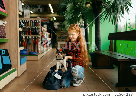 Little girl puts her puppy in bag, pet store 61504288