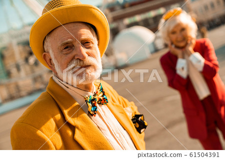 Smiling old man in hat looking at camera outdoors 61504391