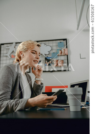 Pretty female is holding mobile phone at workplace Pretty female is holding mobile phone at workplace 61508167