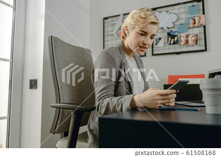 Smiling pretty woman using mobile phone in the office 61508168
