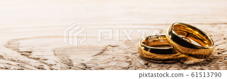 Golden wedding rings on wood 61513790