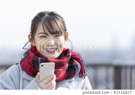 Young woman smiling with smartphone in hand 61518827
