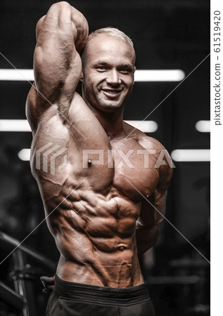 Handsome strong athletic man pumping up muscles 61519420
