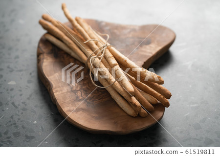 bunch of handmade wholegrain grissini tied with rope on olive board 61519811