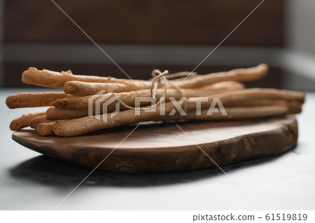 bunch of handmade wholegrain grissini tied with rope on olive board 61519819