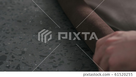 man rolling brown leather piece and take it away closeup man rolling brown leather piece and take it away closeup 61520255