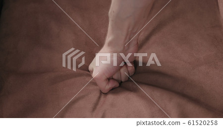 man hand checking brown suede cushion closeup man hand checking brown suede cushion closeup 61520258