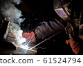 worker welds metal structures by electric arc 61524794