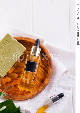 Cosmetic bottle with serum or hyaluronic acid and olive soap, Omega-3 gel capsules on wooden plate , palm leaf, on a white towel Cosmetic bottle with serum or hyaluronic acid and olive soap, Omega-3 gel capsules on wooden plate , palm leaf, on a white towel 61526704