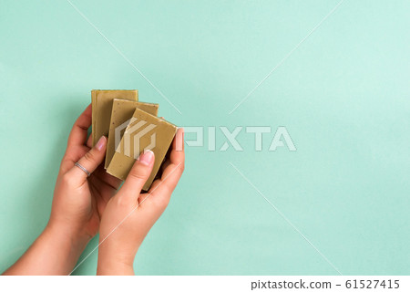 Woman hands holding natural organic solid green soap bar made with olive oil on blue background. Healthy lifestyle, beauty, skin care. Zero waste home concept. 61527415