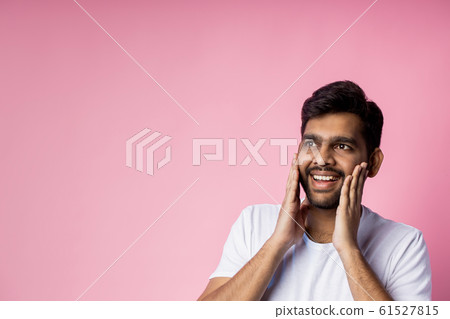 Portrait of handsome Indian guy standing on pink 61527815