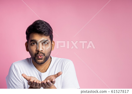 Portrait of handsome Indian guy standing on pink 61527817