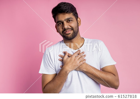 Portrait of handsome Indian guy standing on pink 61527818