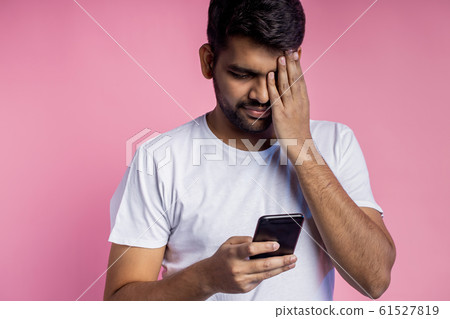 Portrait of handsome Indian guy standing on pink 61527819