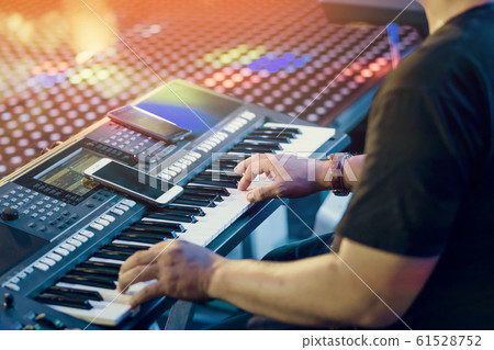 Musician play electronic keyboard synthesizers by using smartphone as guidelines for playing on the concert stage. Selective focus on smartphone. Musician play electronic keyboard synthesizers by using smartphone as guidelines for playing on the concert stage. Selective focus on smartphone. 61528752