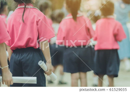 Back view of little girls use paper rolls instead of long cheerleader Baton Sticks for school parade marching practice. 61529035