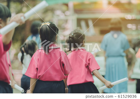 Back view of little girls use paper rolls instead of long cheerleader Baton Sticks for school parade marching practice. Back view of little girls use paper rolls instead of long cheerleader Baton Sticks for school parade marching practice. 61529036