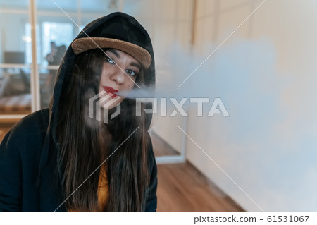Vaping girl. Young hipster woman vape e-cig at the vapeshop. Hip-hop style. Closeup. 61531067