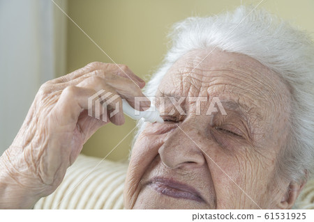 a senior woman applying eyedrops into her eyes a senior woman applying eyedrops into her eyes 61531925