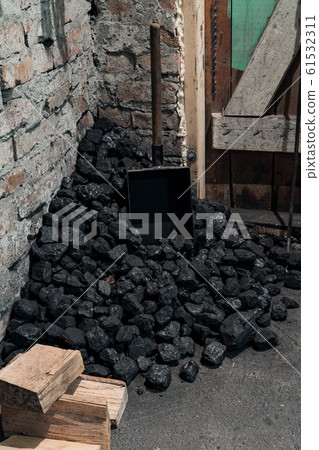 Coal, wood and shovel on the floor at the basement prepared for heating the house with. Coal, wood and shovel on the floor at the basement prepared for heating the house with. 61532311