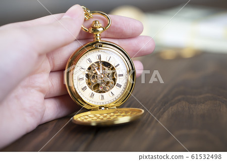 A man holds a vintage pocket watch in his hand. A man holds a vintage pocket watch in his hand. 61532498