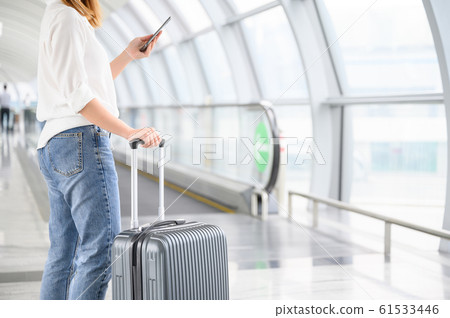 A woman with hand luggage walking in airport 61533446