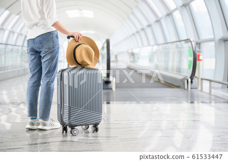 A woman with hand luggage walking in airport A woman with hand luggage walking in airport 61533447