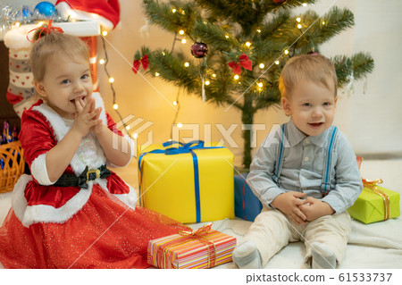 Family on Christmas eve at fireplace. Mother and little kids opening Xmas presents. Children with gift boxes. Living room with traditional fire place and decorated tree. Cozy winter evening at home. Family on Christmas eve at fireplace. Mother and little kids opening Xmas presents. Children with gift boxes. Living room with traditional fire place and decorated tree. Cozy winter evening at home. 61533737