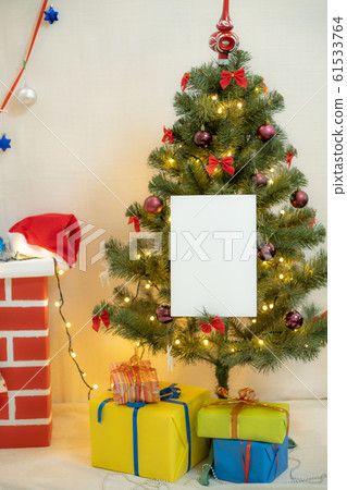 White blank sheet of paper against the background of the Christmas tree and the fireplace White blank sheet of paper against the background of the Christmas tree and the fireplace 61533764