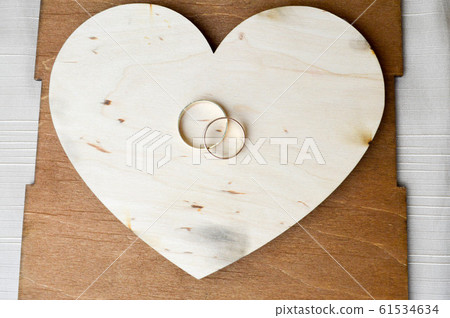 Gold wedding rings on a wooden heart. Gold wedding rings on a wooden heart. 61534634