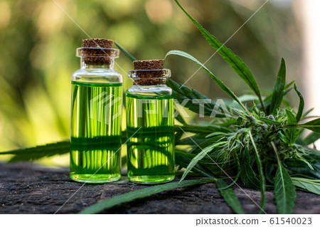 On fireGlass bottle with CBD oil and cannabis blossom at the background, medical marijuana concept flames at the black background 61540023