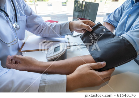 The male doctor measured blood pressure, the patient examined the heartbeat and talked about health care closely The male doctor measured blood pressure, the patient examined the heartbeat and talked about health care closely 61540170