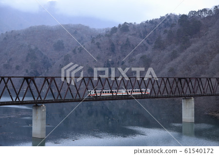 Train crossing dam lake in winter 61540172