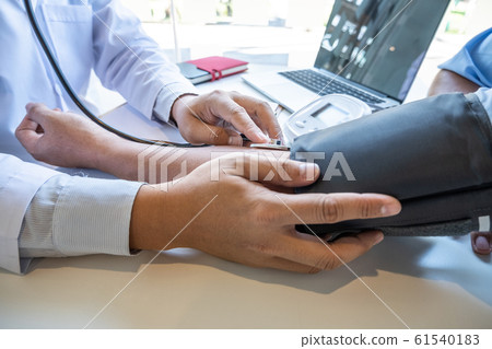The male doctor measured blood pressure, the patient examined the heartbeat and talked about health care closely The male doctor measured blood pressure, the patient examined the heartbeat and talked about health care closely 61540183
