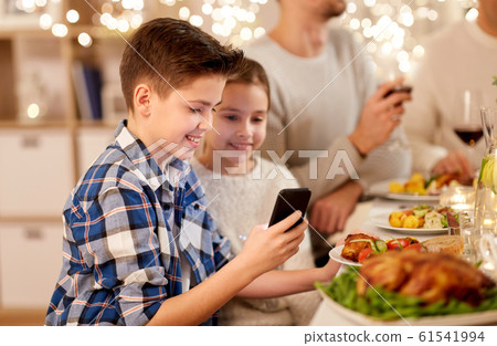 boy with sister using smartphone at family dinner boy with sister using smartphone at family dinner 61541994