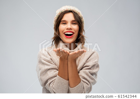 young woman in knitted winter hat sending air kiss 61542344