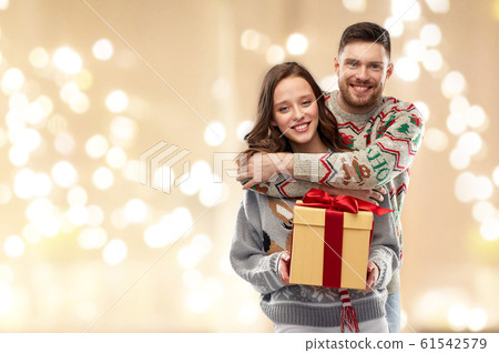happy couple in christmas sweaters with gift box happy couple in christmas sweaters with gift box 61542579