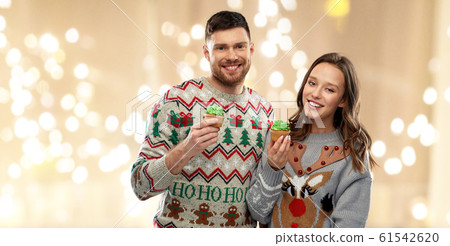 couple with cupcakes in ugly christmas sweaters 61542620