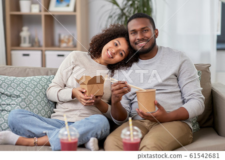 happy couple with takeaway food and drinks at home 61542681