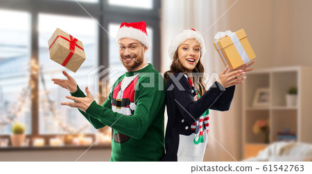 happy couple in christmas sweaters with gifts happy couple in christmas sweaters with gifts 61542763